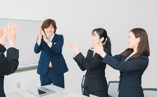 成果を上げた社員をチーム全員で祝っている場面